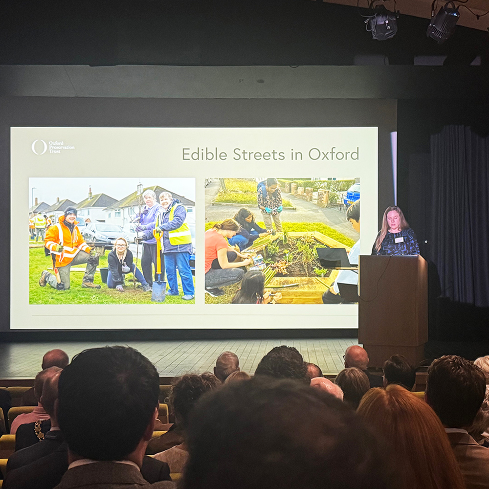 251120 Edible Streets highly commended at OPT awards_1 Person on stage with Edible Streets on the projector screen