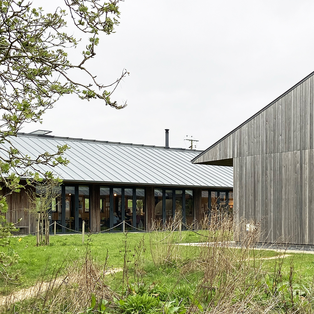 260326 Hemp Construction at FarmED_1 Two FarmED buildings with timber-clad walls and zinc roofs